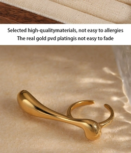Detailed macro view of a gold PVD plated fluid teardrop ring with mirror-like finish