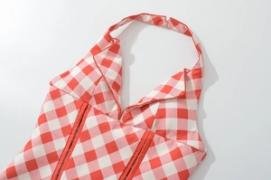 Macro view of red plaid halter top showing detailed structural stitching and fabric texture