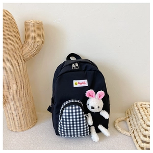 Close-up of children's black backpack with checkered pocket and plush rabbit charm