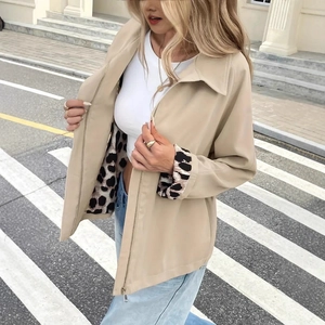 Detail of khaki jacket with leopard print cuffs and metal zipper closure on the street