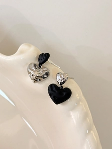 Detail of asymmetric liquid metal heart earrings in contrasting silver and black colors