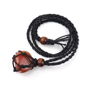 Macro detail of natural reddish-brown raw stone in handcrafted black woven necklace pouch