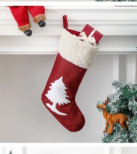 Close-up of a red burlap Christmas stocking with a white tree on a white mantelpiece
