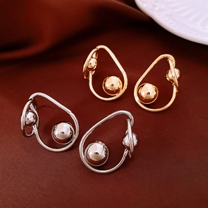 Détail de boucles d'oreilles torsadées avec perles en métal sur soie foncée