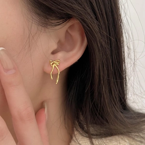 Elegant gold bow earrings for women shown as a close-up side view of a model wearing them