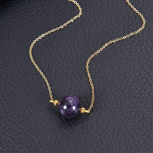 Detailed macro view of a 16mm round purple crystal pendant on a gold chain necklace