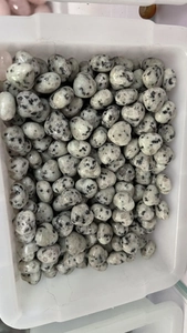 Macro shot of 15mm white heart-shaped natural crystal stones with black spots in a box