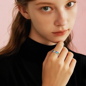 Rainbow striped stainless steel spinner ring for women on a soft pink background