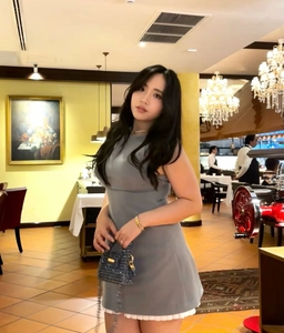 Ärmelloses graues Kleid mit weißem Faltenrock in einem eleganten Restaurant-Ambiente
