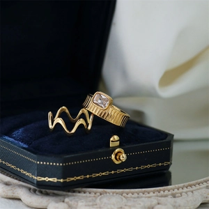 Detail of 18K gold wavy and textured gear rings with a rectangle zircon on blue velvet