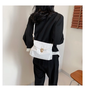 Rear view of model wearing a minimalist white leather crossbody bag with gold hardware