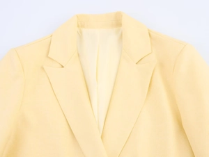 Detail of classic notched lapel and front placket on pale yellow blazer jacket