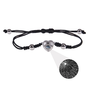 Détail du bracelet tressé noir avec pendentif cœur montrant la projection de 100 langues