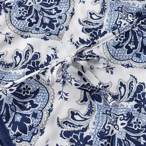 Detailed view of blue and white paisley print fabric and tie-front knot closure detail