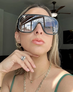 Selfie view of oversized black sunglasses with gold earrings and layered rings on person