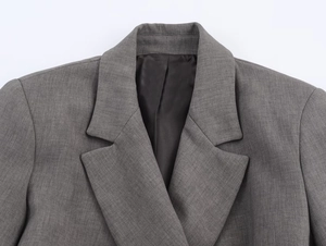 Gros plan du col d'une veste de costume grise montrant la texture fine du tissu et les coutures