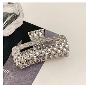 Macro shot of silver quilted metal hair claw clip with glossy polished finish