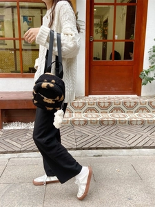 Petit sac à dos en peluche noire avec motif et pompon pour femmes style décontracté