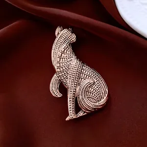 Artistic cat brooch in rose gold finish with textured geometric patterns on silk background