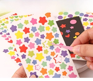 Close-up of heart stickers being applied with tweezers showing the die-cut design
