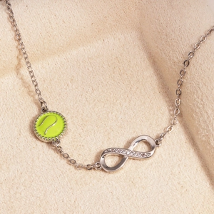 Detailansicht eines Unendlichkeitssymbols und Tennisball-Anhängers an einem Silberarmband