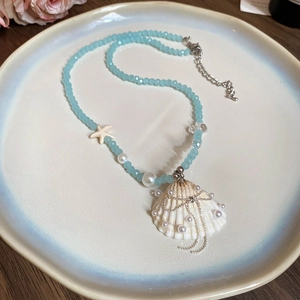Collana a strati con perline azzurre, ciondolo a conchiglia e dettagli in perle