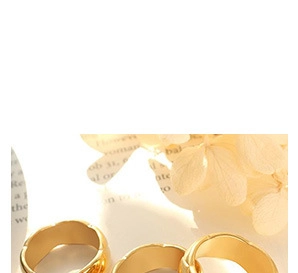 Detailed view of three gold textured rings featuring wave patterns on minimalist cards