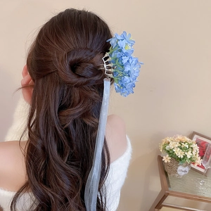 Detailed close-up of a blue fabric flower hair pin with elegant translucent silk ribbons