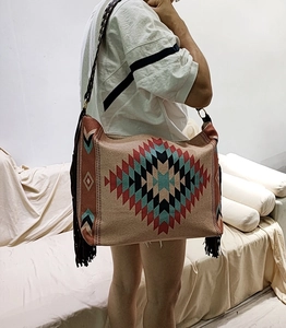 Detail of bohemian woven shoulder bag featuring geometric patterns and long side tassels