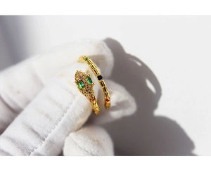 Detailed close-up of golden snake ring with green red blue stones and pavé set crystals