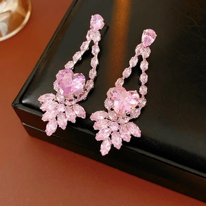 Gros plan de boucles d'oreilles cœur en zircon rose sur boîte à bijoux noire
