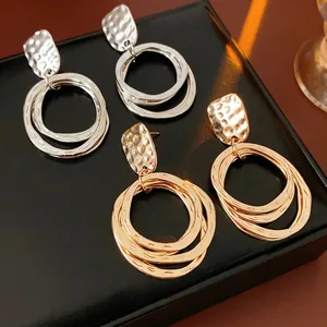 Gold and silver geometric layered hoop earrings with hammered texture on a black display