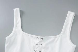 Close-up of white knitted crop top showing front lace-up design and metal eyelet details