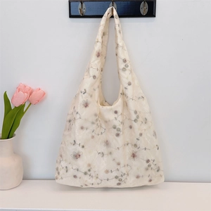 Close-up of a cream canvas tote bag with delicate floral embroidery and shoulder strap