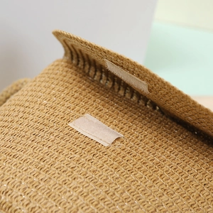Close-up of natural straw weave texture and white Velcro closure detail on a shell bag