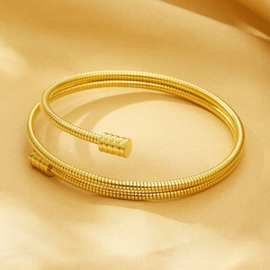 Macro shot of gold plated stainless steel cable spring bracelet on satin background