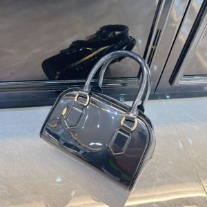 Close-up of black patent leather boston bag with golden hardware and polished surface