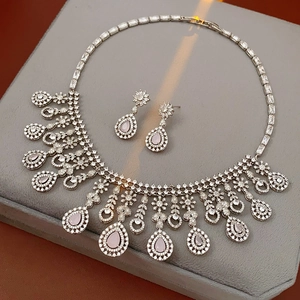 Detailed view of silver jewelry set with pink teardrop stones on gray velvet padding