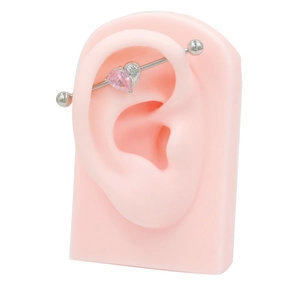 Detailed view of pink heart zircon industrial barbell with wings on a silicone ear model