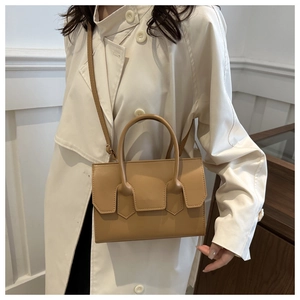 Detail view of beige PU leather handbag with top handle and shoulder strap on model