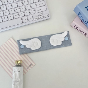 Close-up of grey fabric cable organizer with plush angel wings and button details