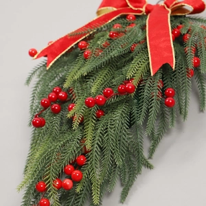 Christmas teardrop swag with red berries and bow hanging on a modern grey wall