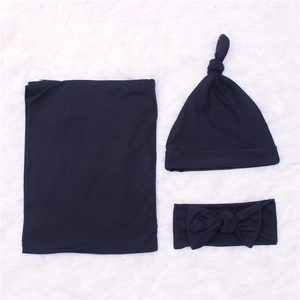 Three-piece newborn set with dark blue swaddle blanket, knot hat, and bow headband