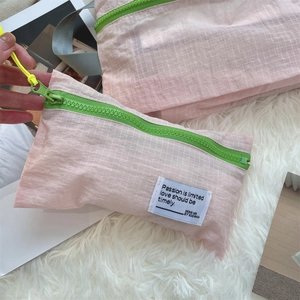 Macro detail of pink checkered nylon waterproof travel organizer bags with green zippers