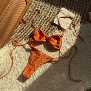Detailansicht eines glänzenden, gebrannten orangefarbenen Bikinis mit Metallic-Struktur