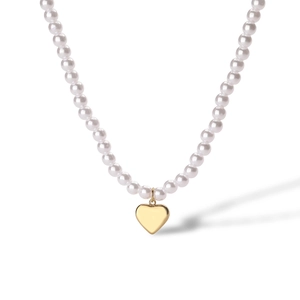 Close-up of a white pearl necklace featuring a polished 18K gold-plated heart pendant