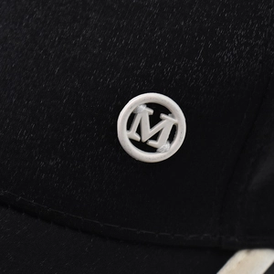 Detailed close-up of a white M logo patch stitched on black fabric twill baseball cap