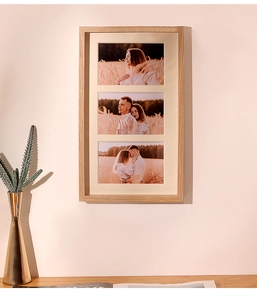 Close-up of triple vertical wooden photo frame with natural grain and beige matting