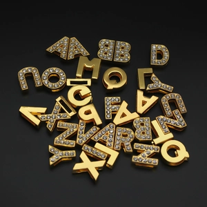 Macro shot of gold-plated alloy letter beads with sparkling rhinestones for DIY jewelry