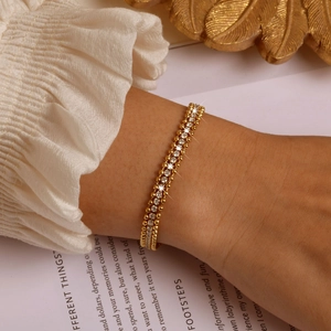 Close-up of gold double-layer chain bracelet with white cubic zirconia on a wrist